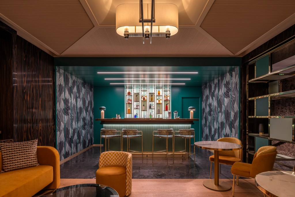 Hilton Turin Centre Alchemy The Bar, tables, orange couch, chairs and bar area with high back chairs and teal decor