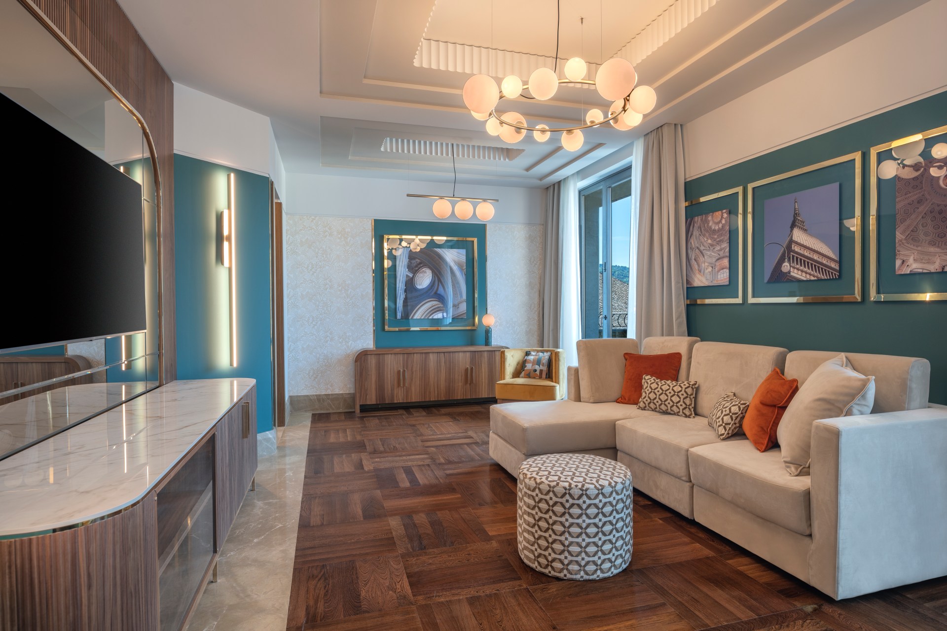 Hilton Turin Centre Presidential Suite Living Room, couch with chaise lounge and ottoman, tv and entertainment system, chandelier photos around walls painted blue and white