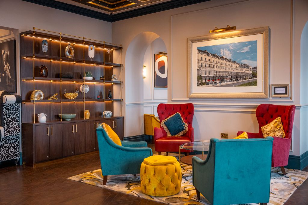 A seating area with a mix of different types of chairs and shelves displaying various sculptural pieces in the lobby of the Dover Marina Hotel &amp; Spa