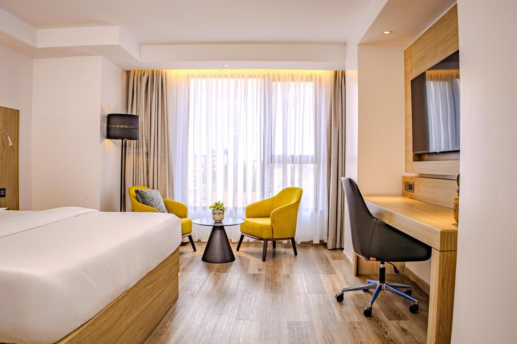 A room with bed, table and chairs, desk, and tv