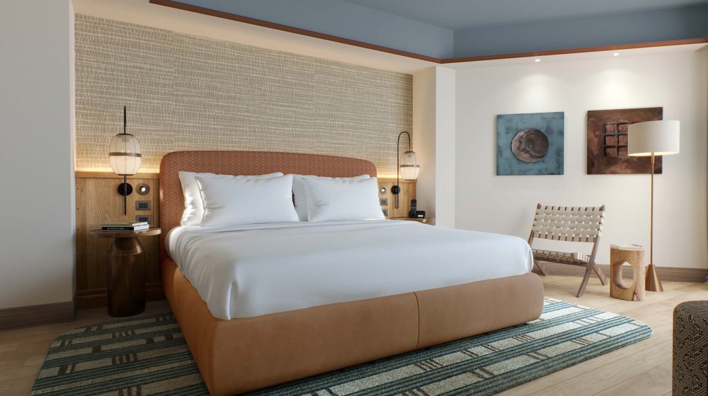 Bedroom with large bed, woven chair, and wall art.