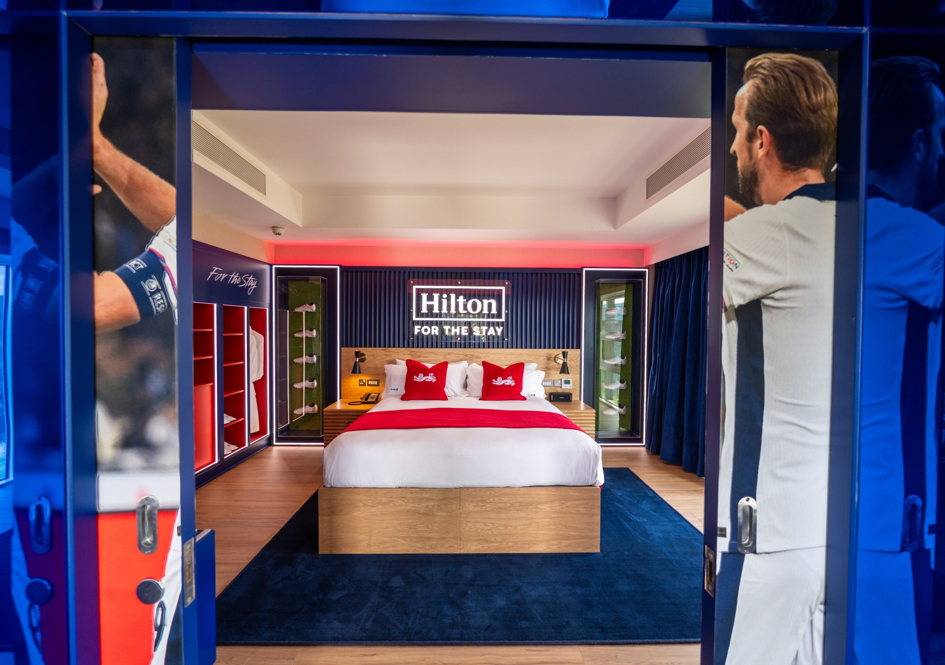 Outside the door of the bedroom, facing the bed framed in memorabilia