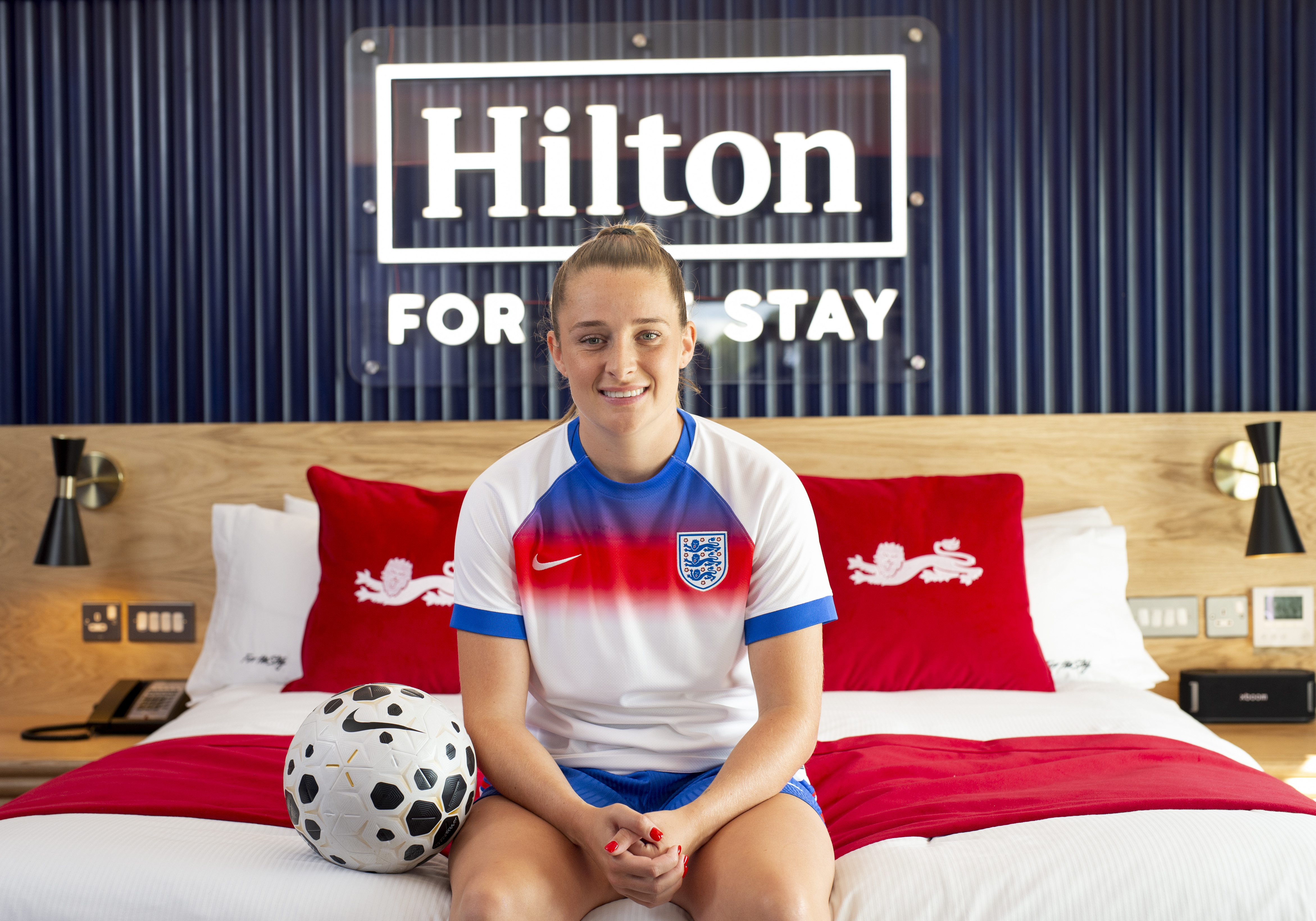 Ella Toone sitting on bed with a football next to her