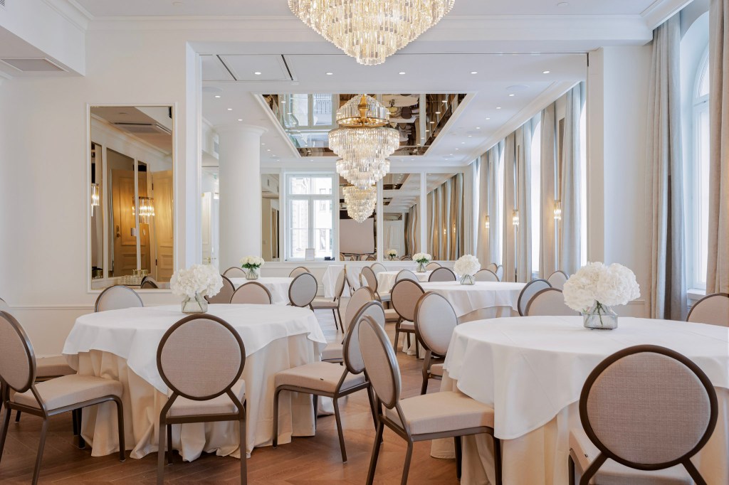 Elegant ballroom with chandeliers and round tables.