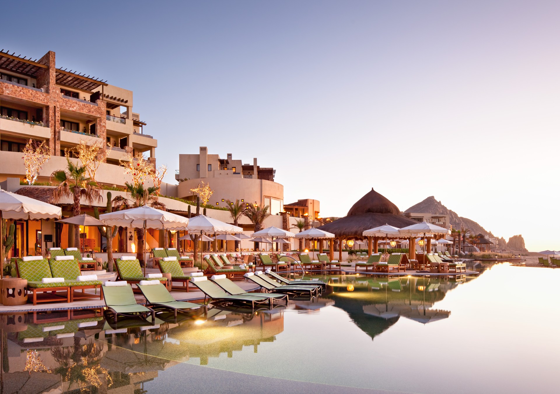 The pool of the hotel, with lounge chairs and umbrellas, with the hotel in the background