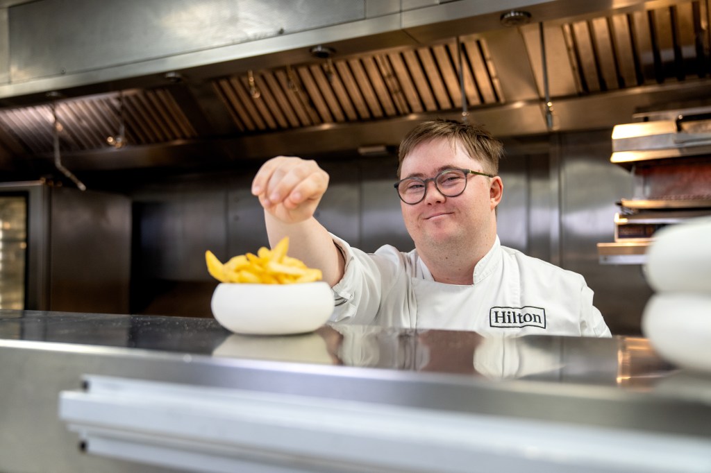 George reaching towards food placed on the kitchen window in front of him