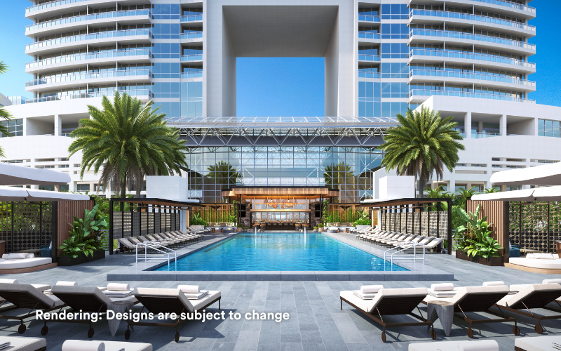 A pool outside the hotel surrounded by pool loungers