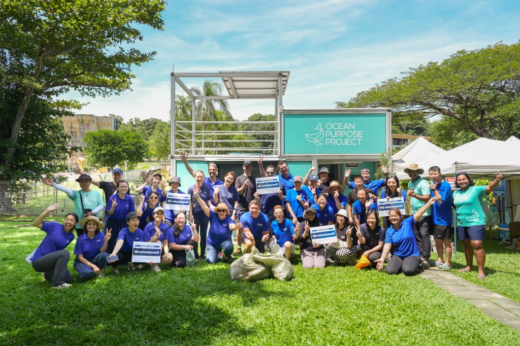 Large group of Hilton team members volunteering with Ocean Purpose Project, holding We Volunteered signs