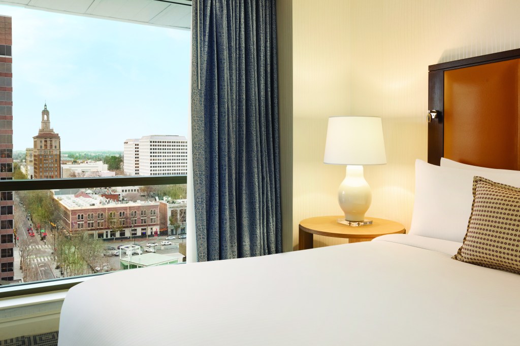 hotel bed and window overlooking city skyline