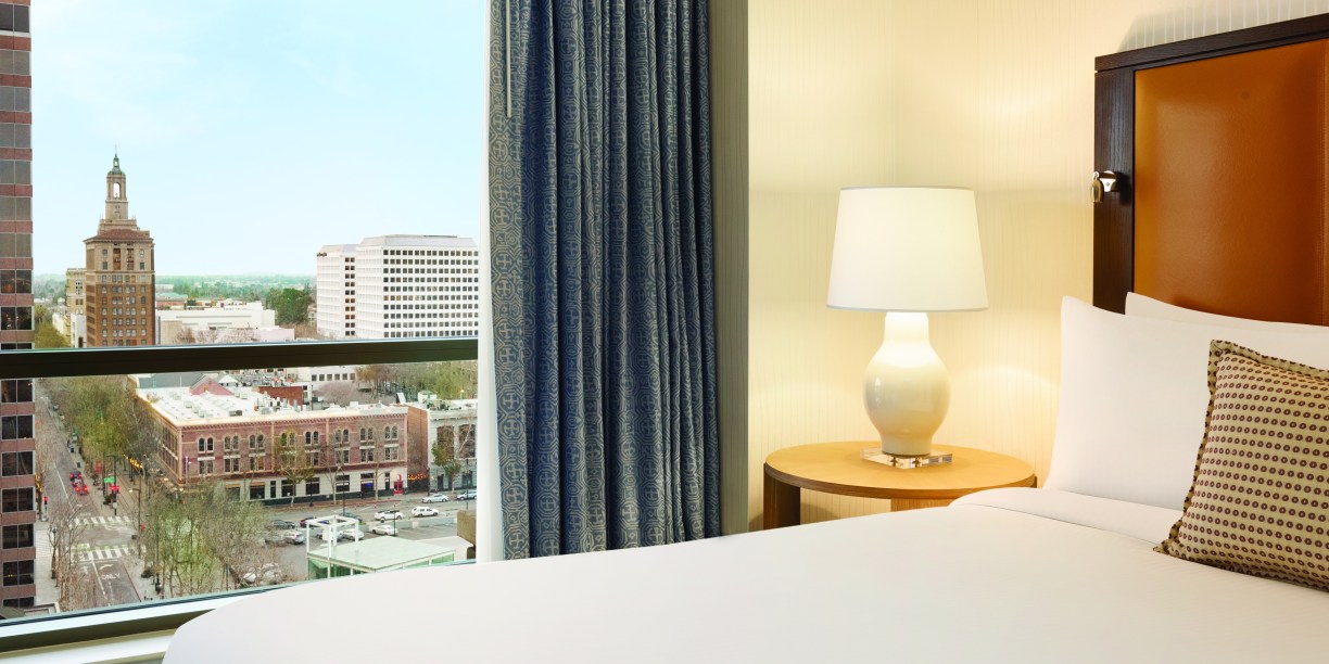hotel bed and window overlooking city skyline
