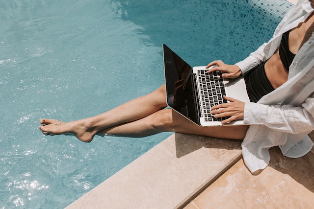 woman working from laptop near a pool