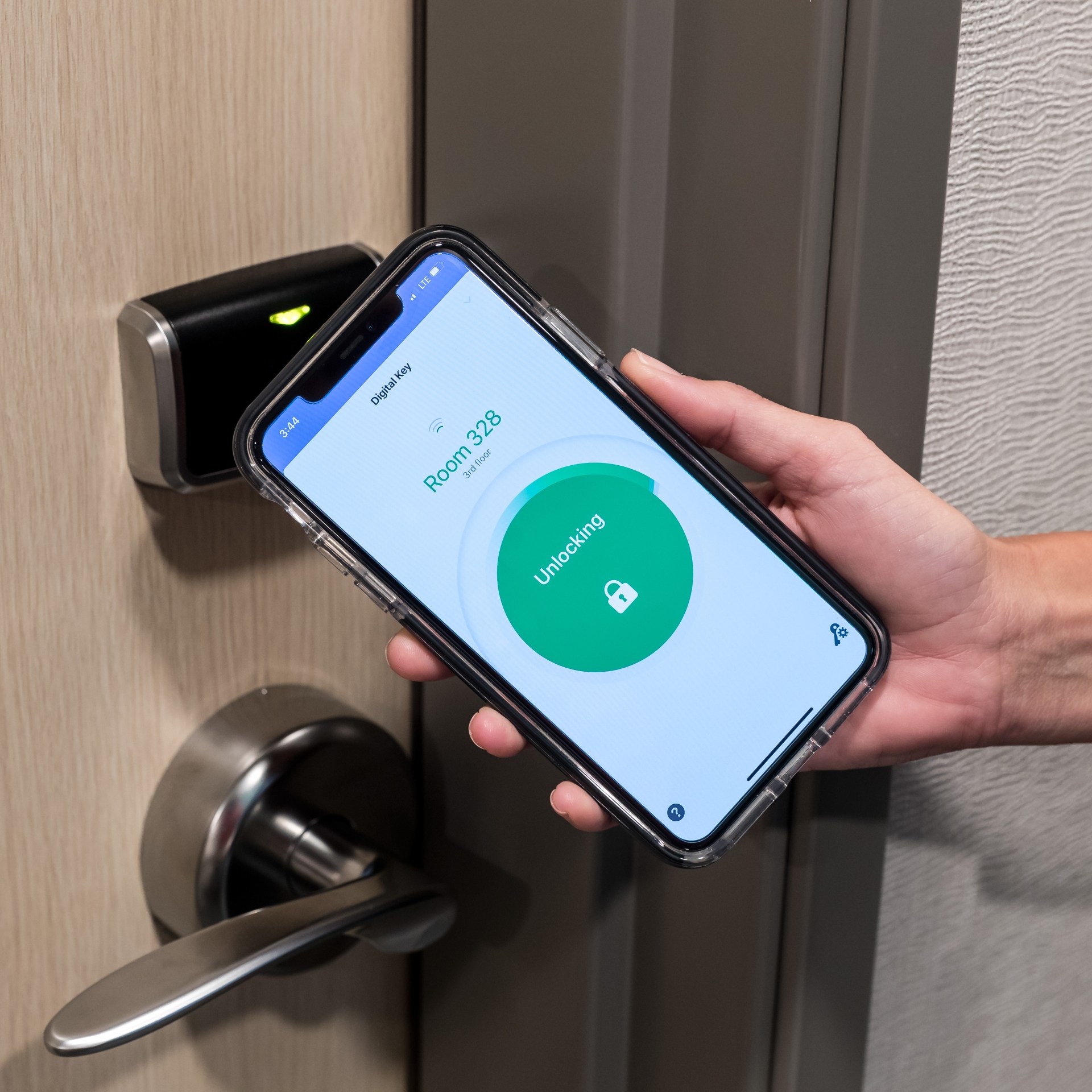 Person holding a phone with Hilton Digital Key activated and opening a hotel room door