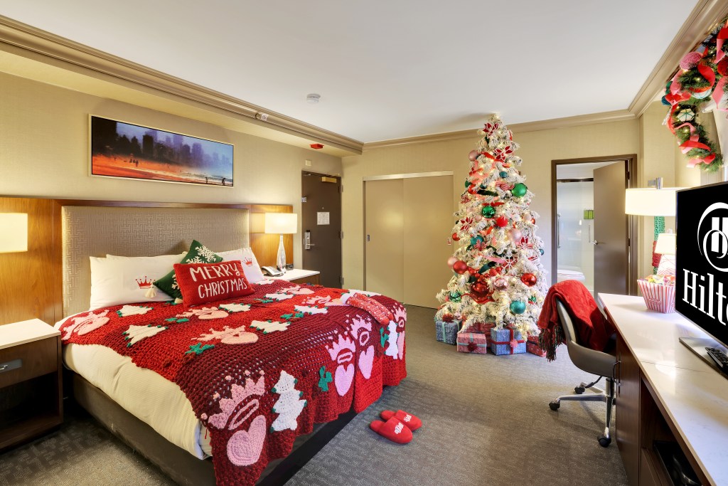 sweater on bed with merry christmas red pillow and hallmark logo at Hallmark Christmas hotel room with xmas decorations at hilton Chicago