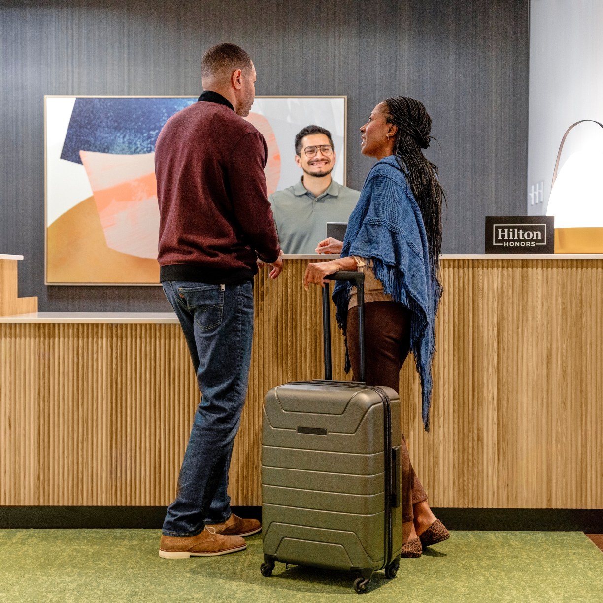 hilton team member greets hotel guests at front desk at Spark by Hilton a new hotel brand