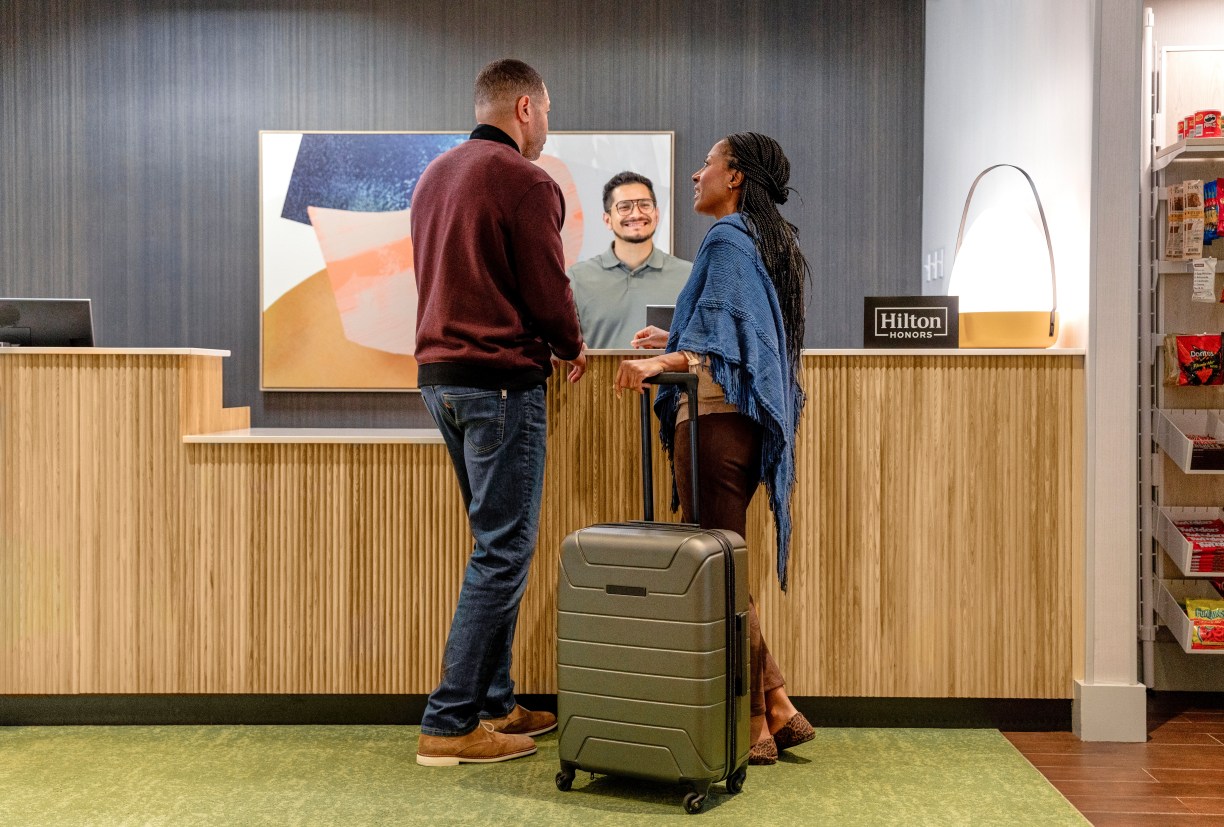 hilton team member greets hotel guests at front desk at Spark by Hilton a new hotel brand