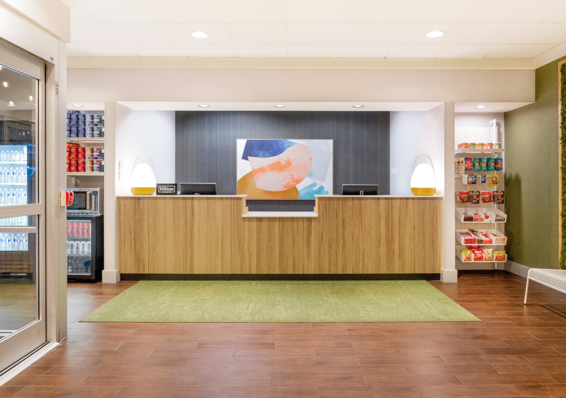 front desk in lobby with modern art and plants on wall at Spark by Hilton a new hotel brand