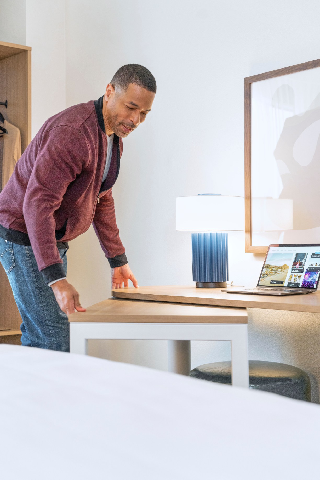 man moves adjustable table in guest room at Spark by Hilton a new hotel brand