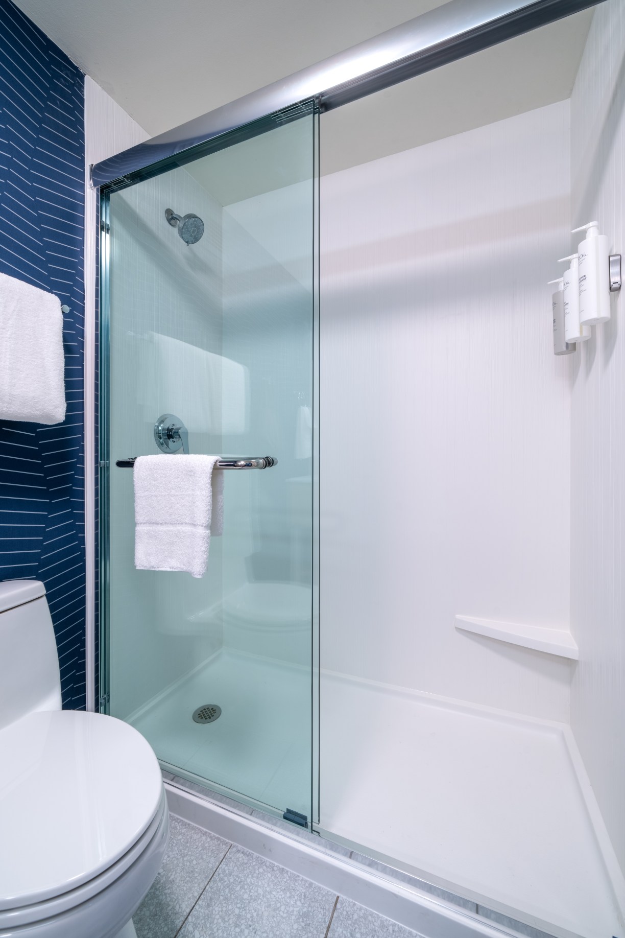 clean guest room bathroom blue white and brown elements at Spark by Hilton a new hotel brand