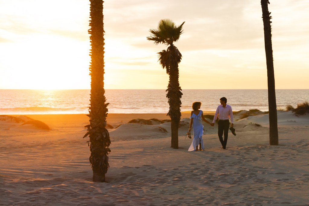 couple walking on the beach during sunset at Zachari Dunes on Mandalay Beach, Curio Collection by Hilton Valentine's Day Deals