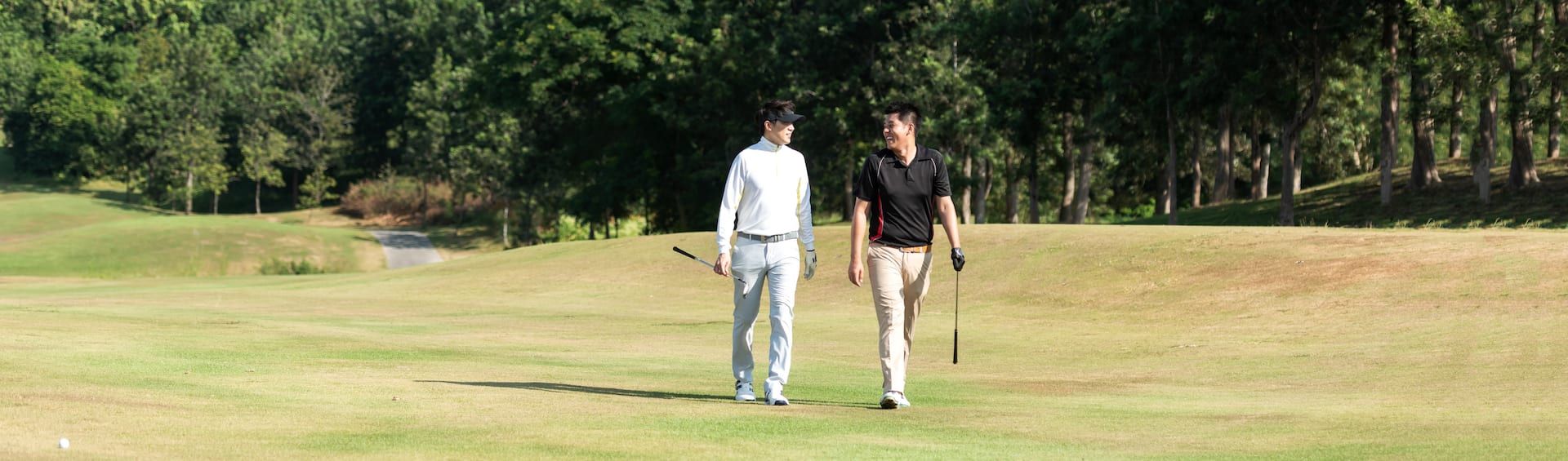 Two men walking down a golf course