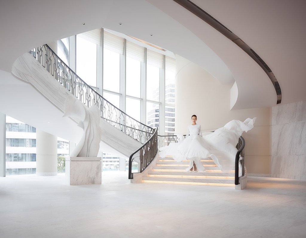 Woman in a white dress walking down stairs; Waldorf Astoria