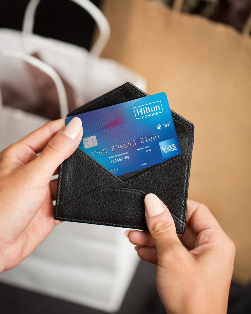 A person pulling a Hilton Honors American Express Credit Card out of their wallet
