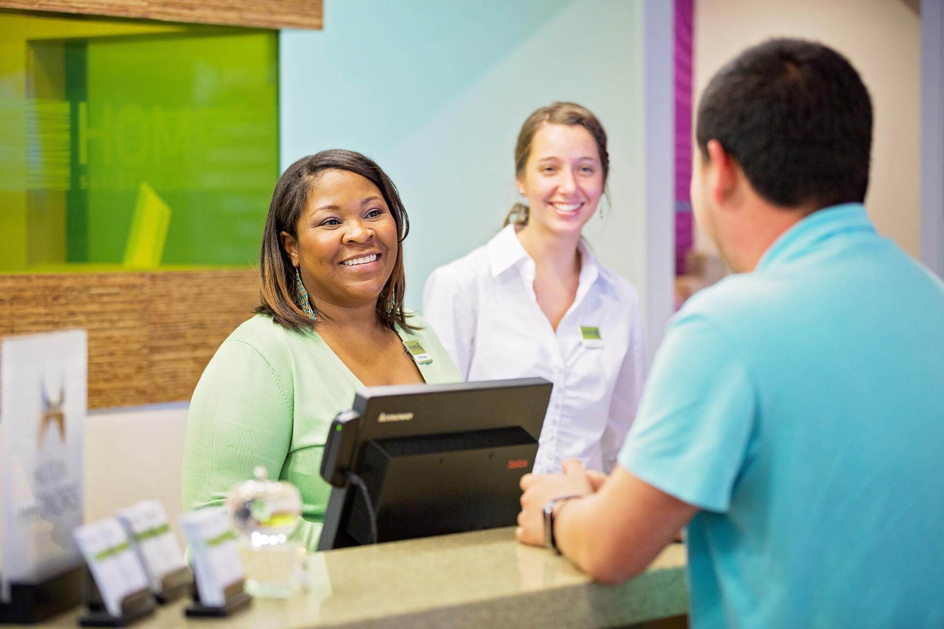 Two smiling employees assisting a guest