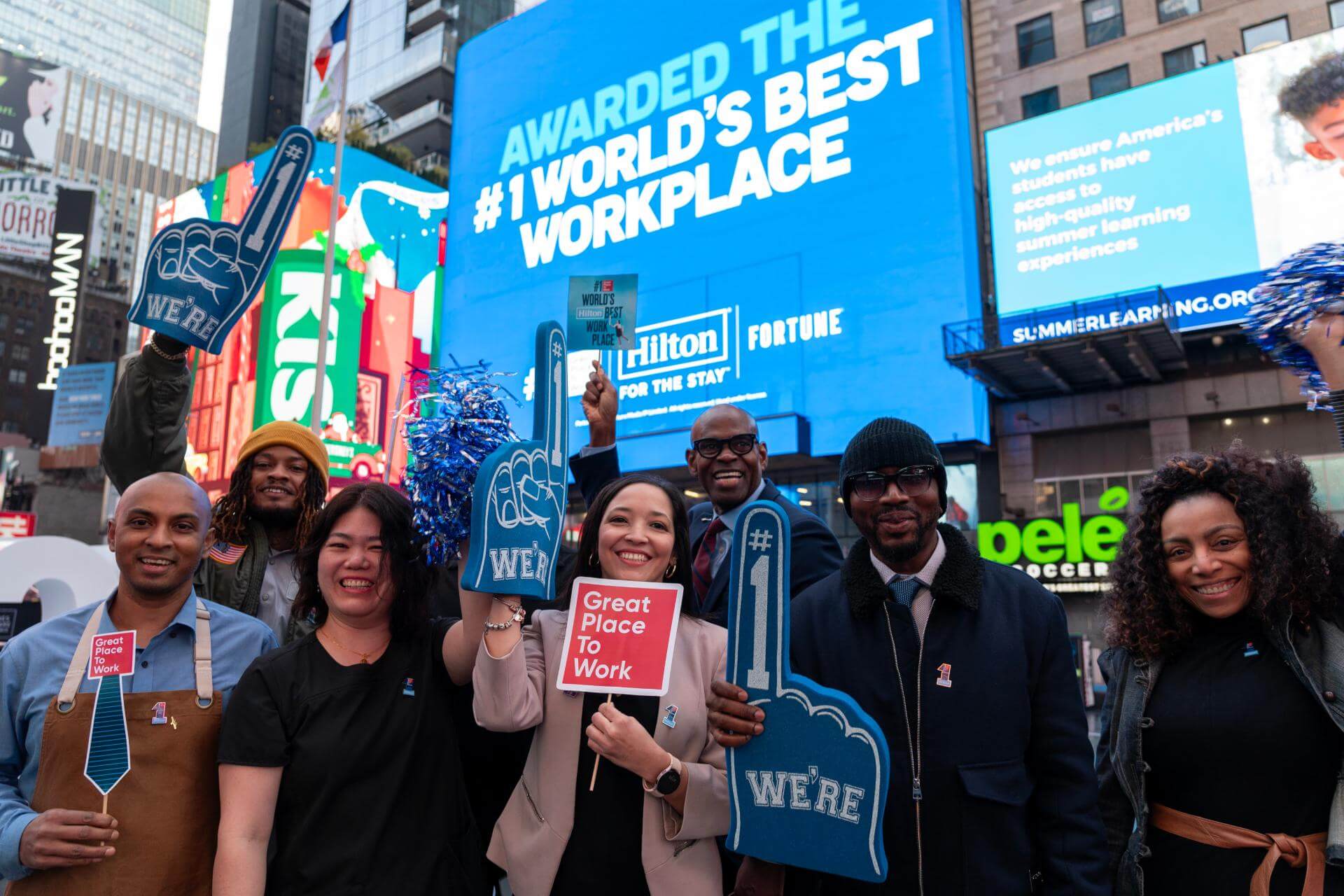 Employees celebrating in front of a billboard for #1 World's Best Workplace