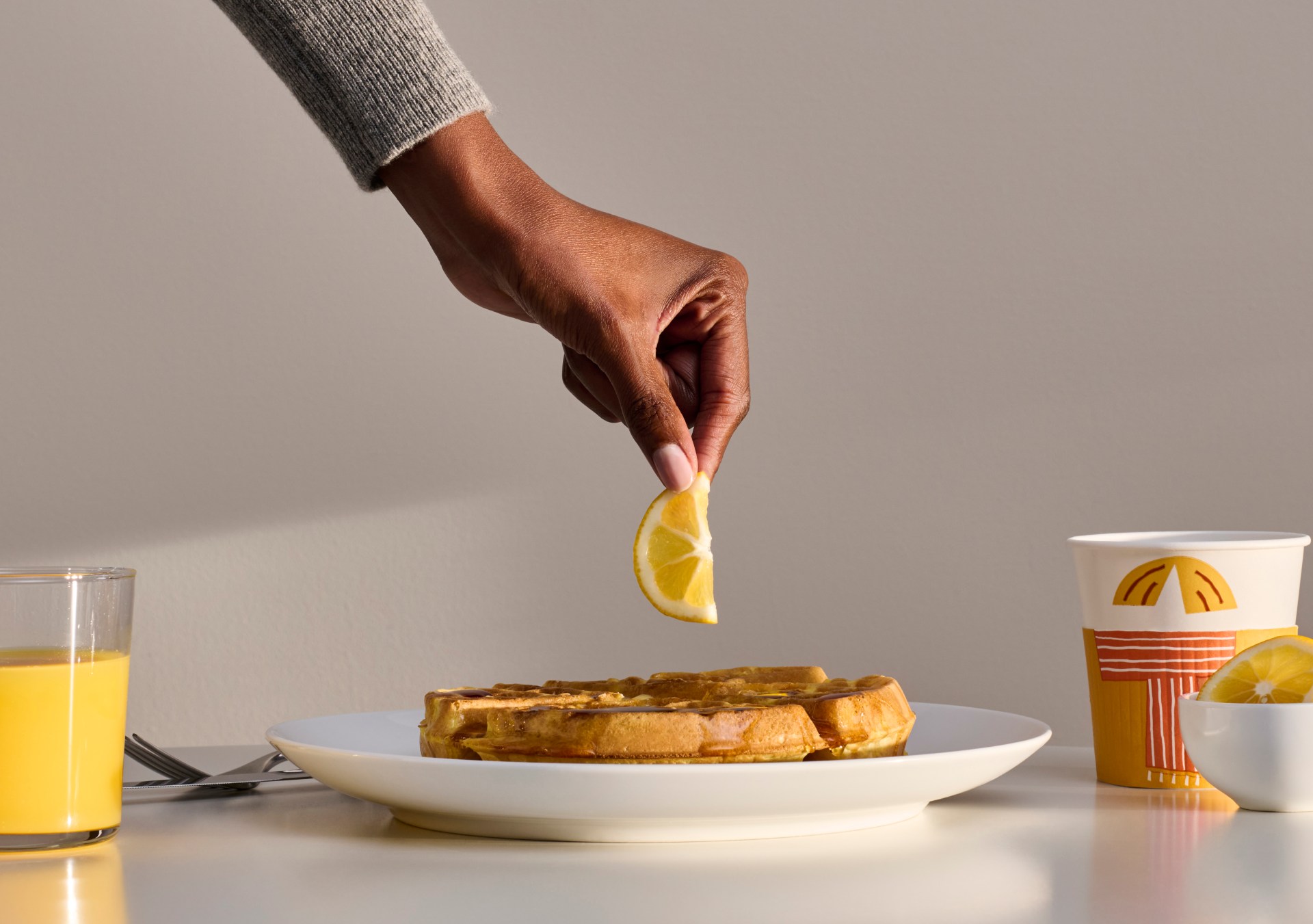 Hampton by Hilton Lemon Waffles - hand holding a lemon over a waffle and breakfast spread