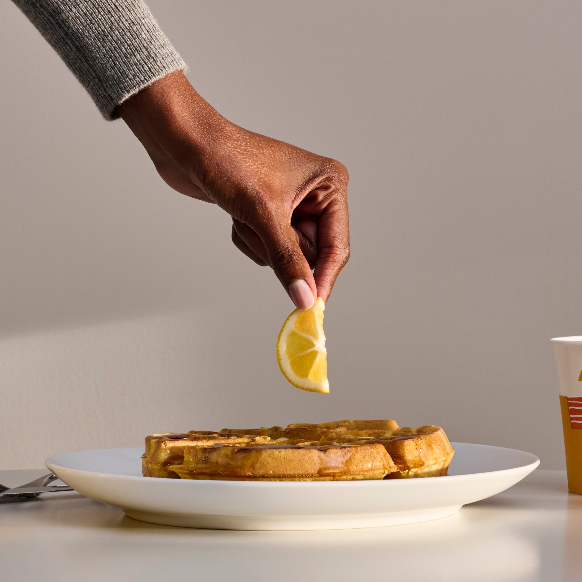 Hampton by Hilton Lemon Waffles - hand holding a lemon over a waffle and breakfast spread