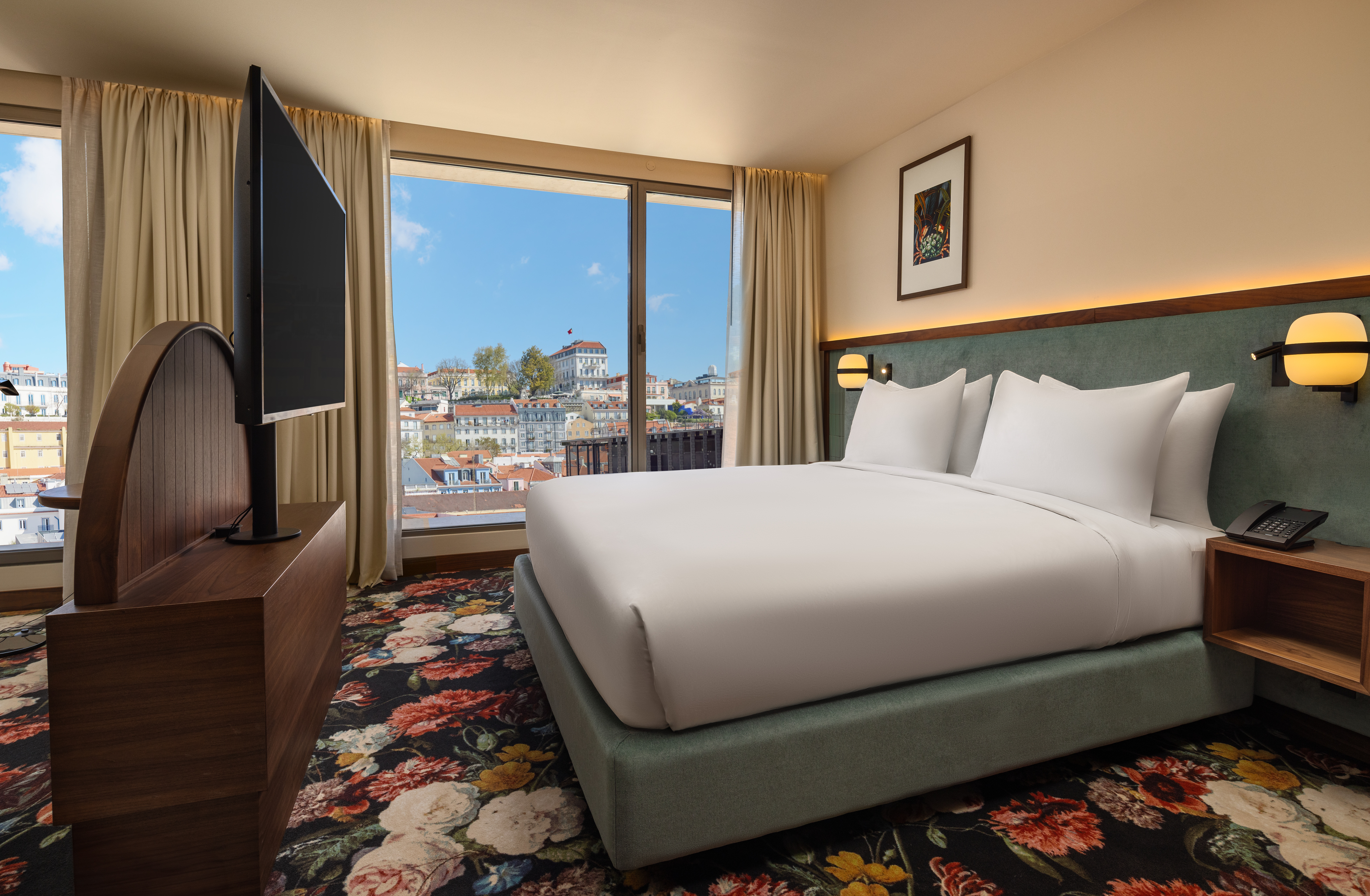 guest room with bed, tv, colorful flower carpet and window looking out at Lisbon - DUO Hotel Lisbon, Curio Collection by Hilton