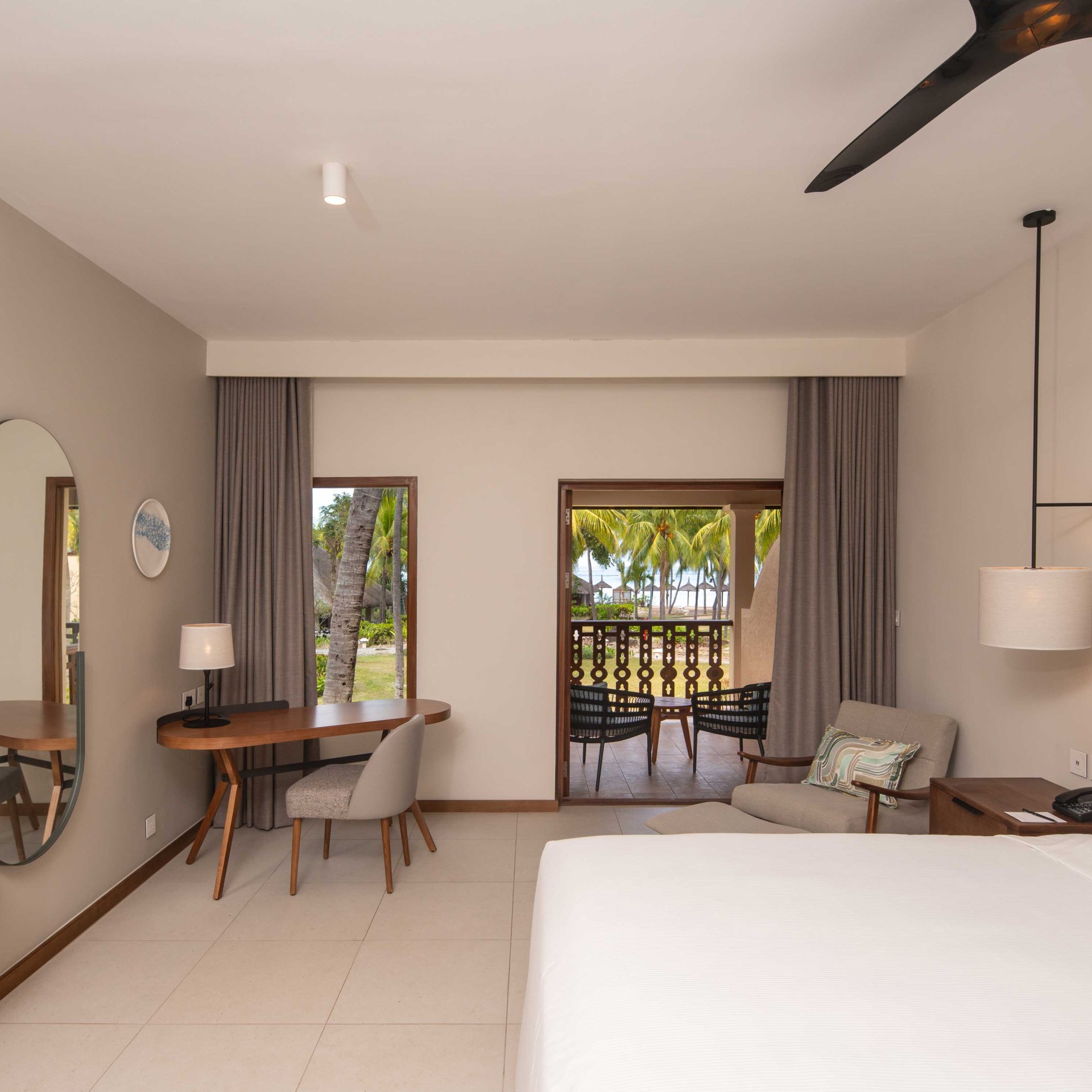 bed, chair, tv, mirror, desk and balcony in deluxe king room at Hilton Mauritius Resort & Spa