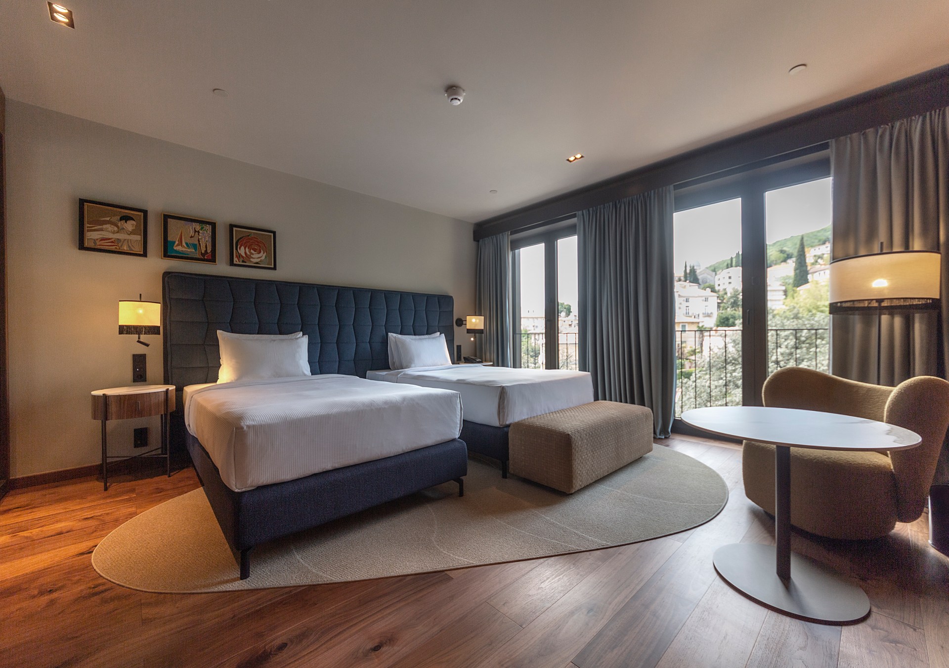 Guest Room with two twin beds, table and chair, large glass doors with view at Keight Hotel Opatija, Curio Collection by Hilton