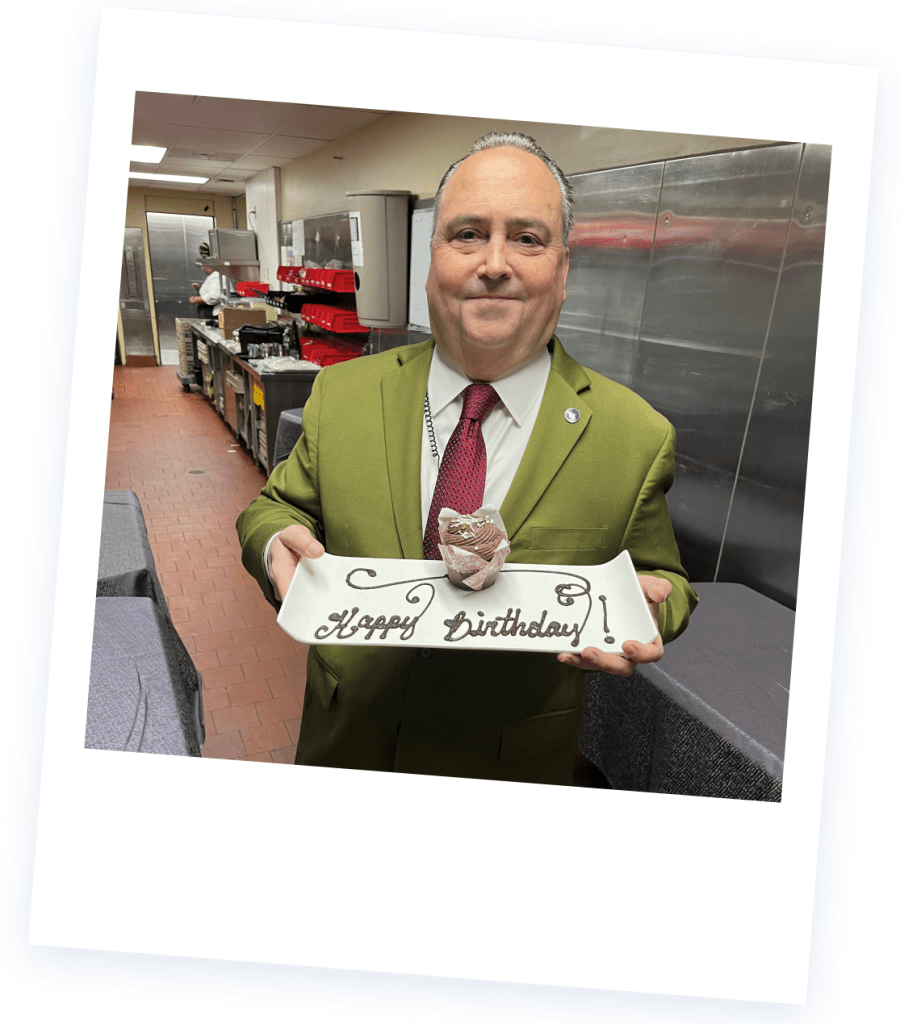 Photo of Christopher Fraizer holding a plate with a birthday cupcake