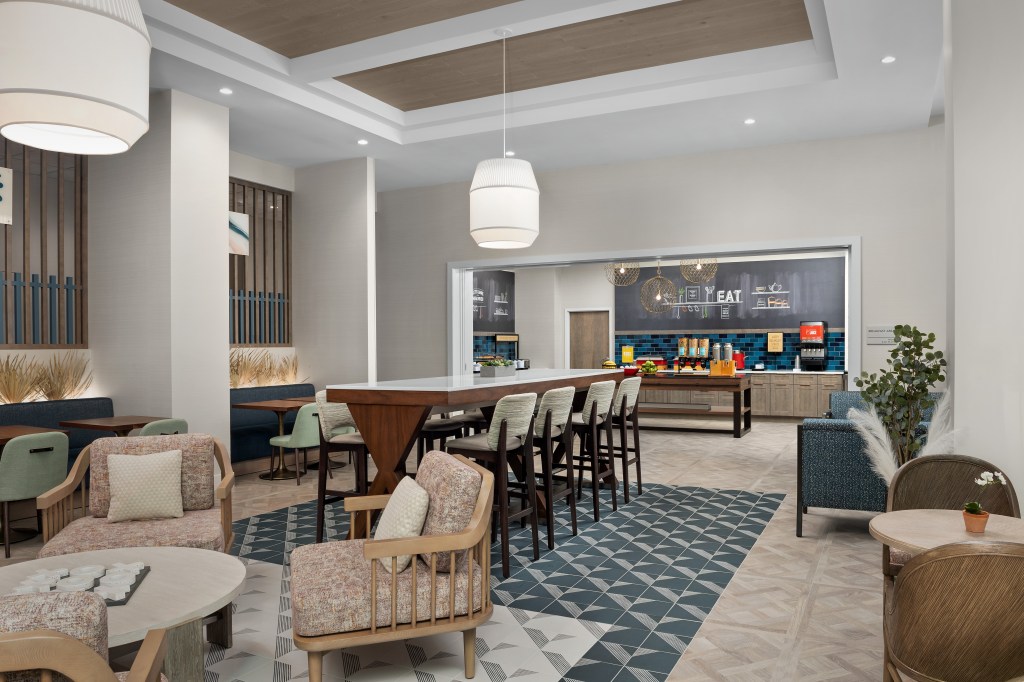 Hampton Inn by Hilton Delray Beach Breakfast seating area, booths, tables, chairs, high-top tables and chairs, beverage and food bar area