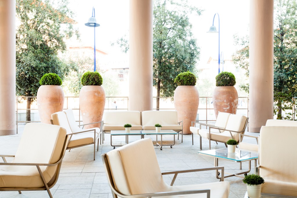 Hilton Garden Inn Florence Novoli - Terrace seating area with chairs and counches, potted shrubs, glass tables