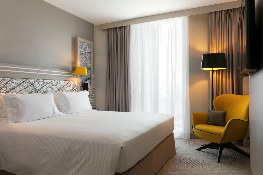 Hilton Garden Inn Paris La Villette Guest Room, bed, chair lamps, tv, window, curtains