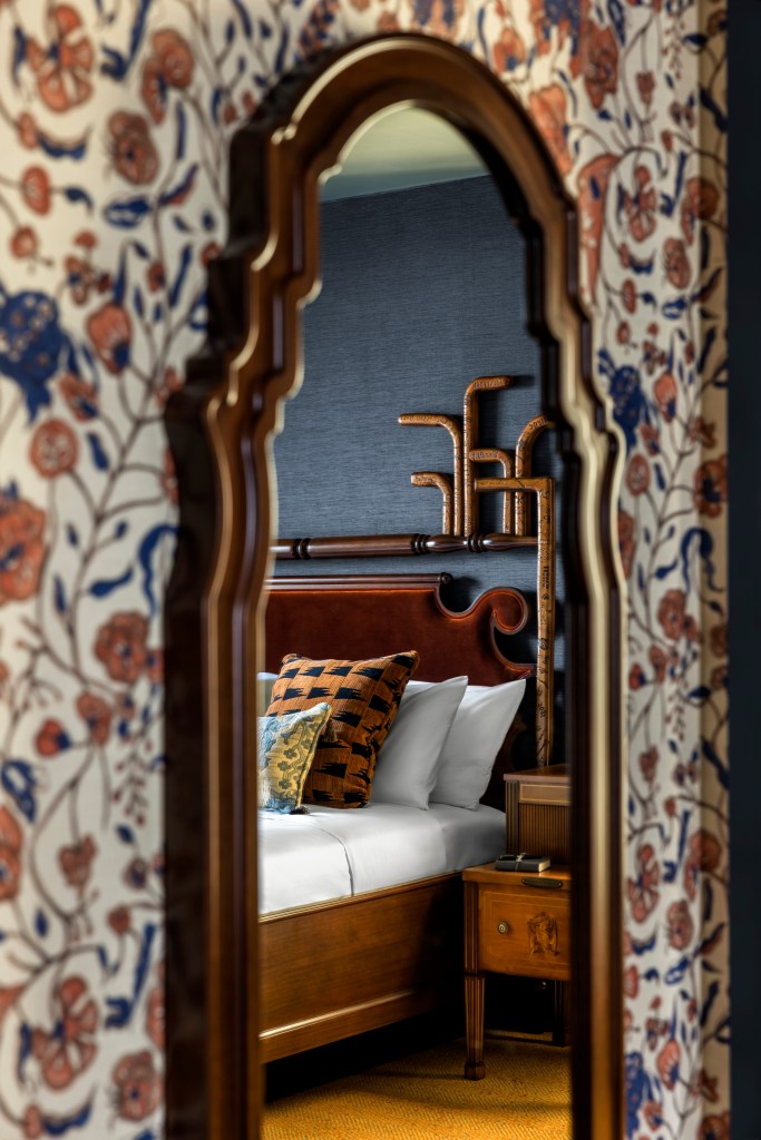 Graduate Princeton Guest Room - photo of a mirror and floral wall paper, can see bed with pillows reflected in mirror