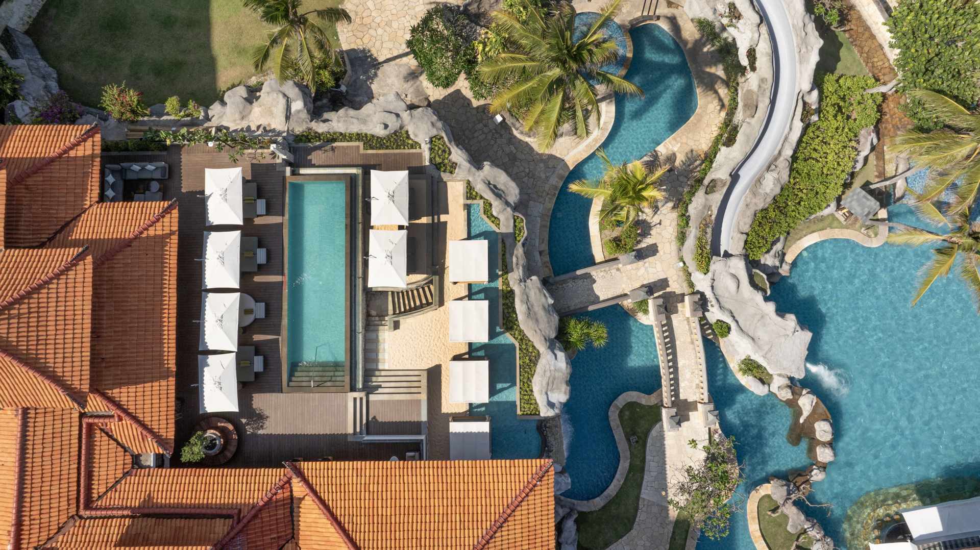 Aerial view of Hilton Bali Resort, pools, landscaping with bridges, palm trees and umbrellas