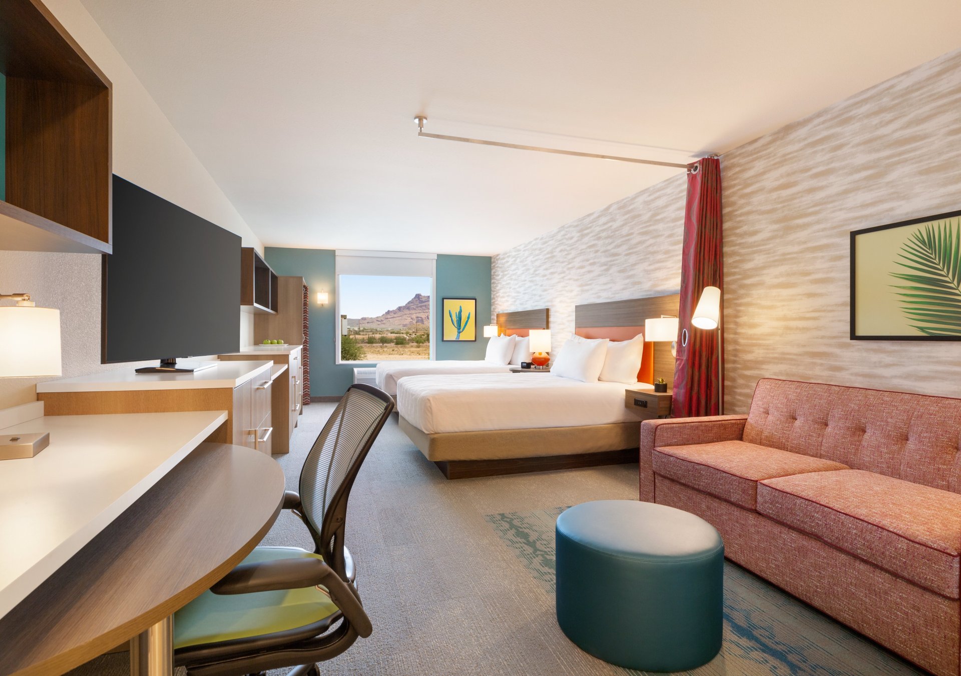 Guest room with sofa, desk and chair, television, two beds, and window looking out at desert scenery at Home2 Suites by Hilton Mesa Longbow