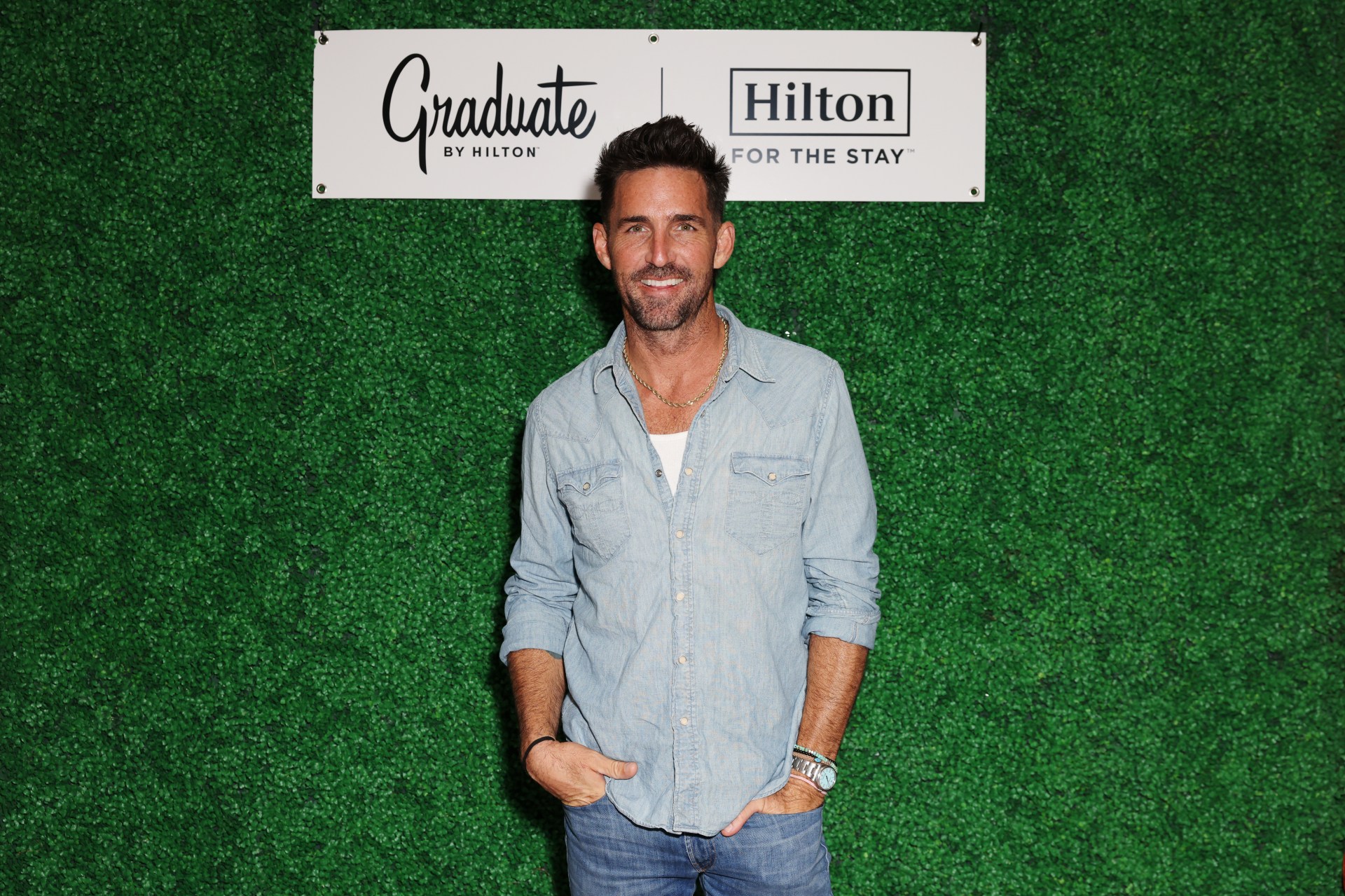 Jake Owen at Graduate by Hilton, Auburn, AL - standing in front of a green wall with Graduate by Hilton and Hilton For The Stay logos