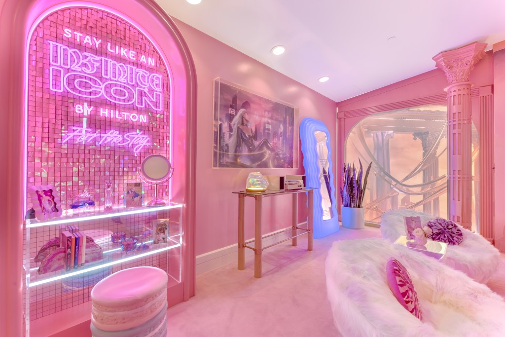 Stay Like an Infinite Icon Themed Suites at Beverly Hilton - Living Room Close Up - living room features pink walls with neon accents, white fuzzy chairs and Paris Hilton memorabilia - Credit Invision Studio for Hilton