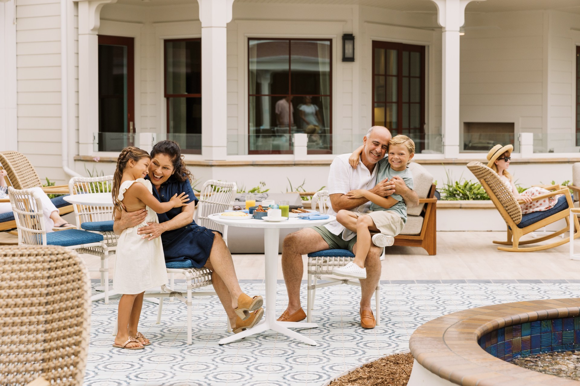 family with children hugging at table in courtyard with breakfast foods