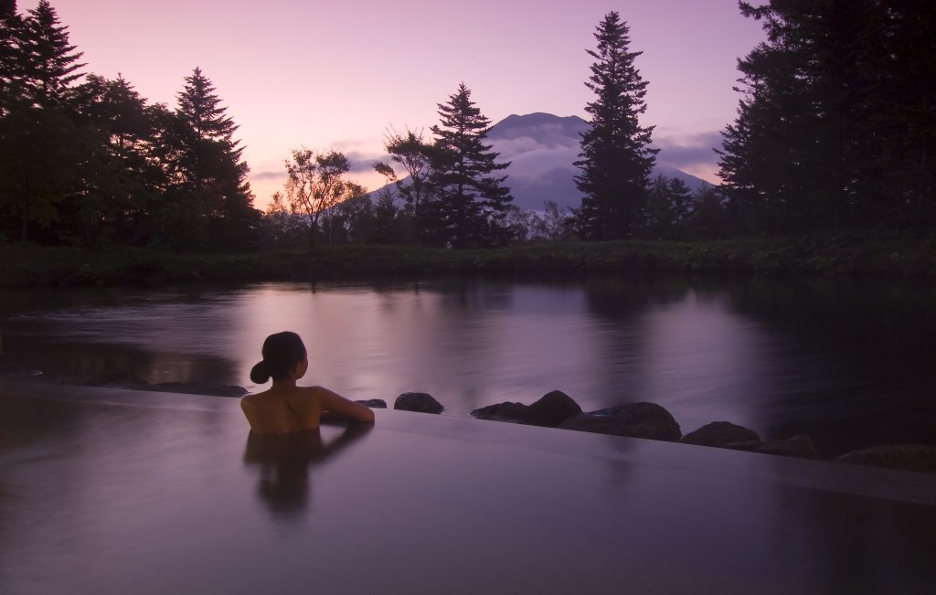 Hilton Niesko Village Onsen, woman in onsen hot springs with dusk view of mountain, Hilton Niseko Village Onsen Sunset