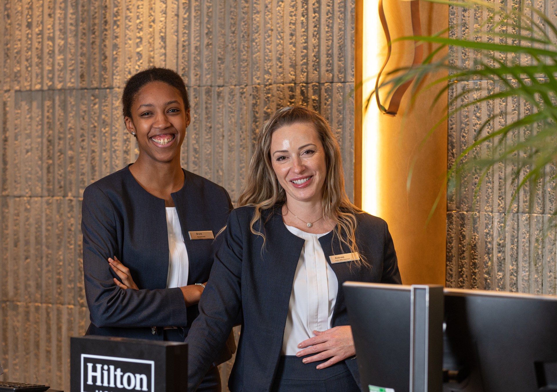two women team members smiling at Hilton front desk