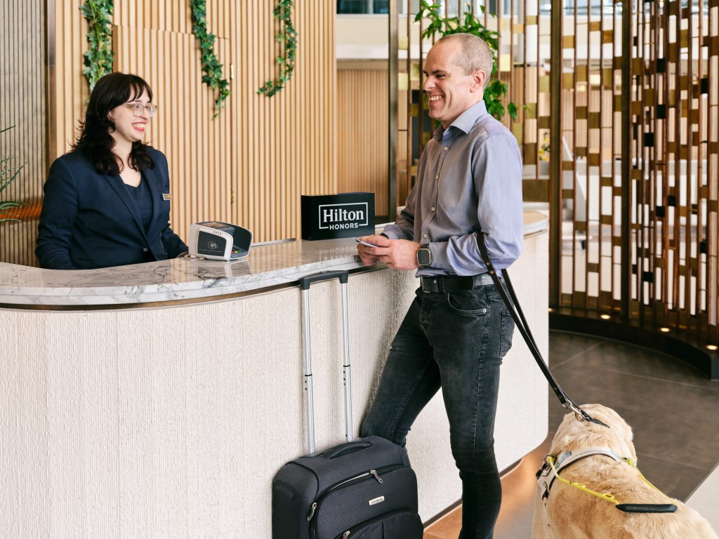 Hilton and Be My Eyes Launch Industry-First Partnership, Check-In Desk, dog, people laughing