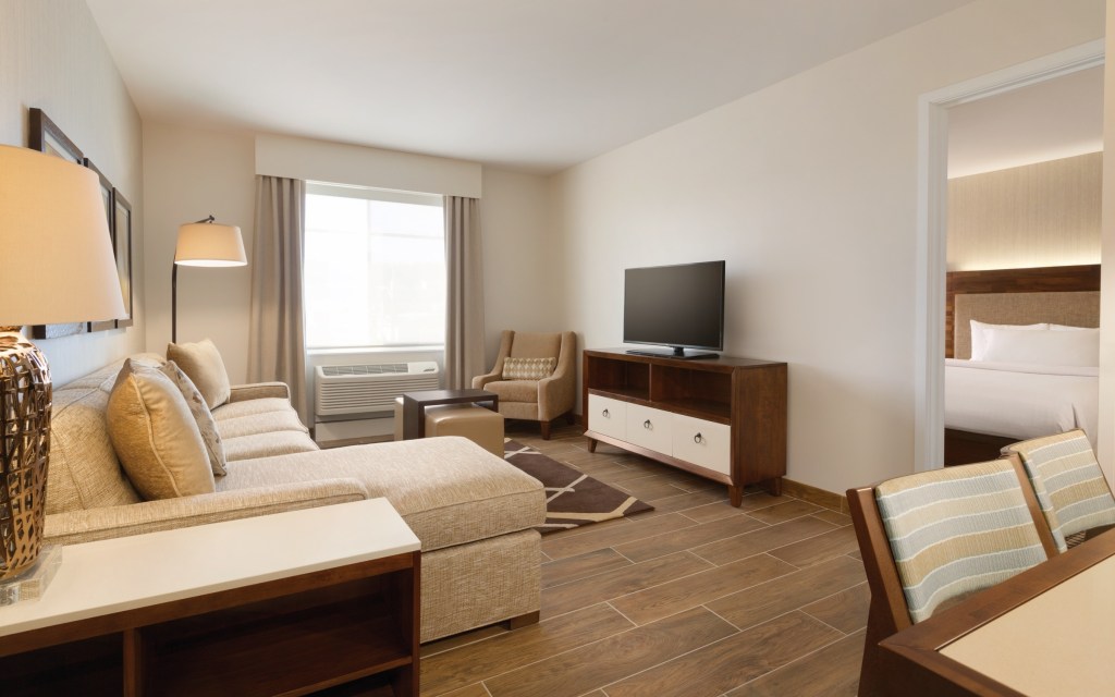 living room area with sectional couch with chaise lounge, side table,  armchair and table, tv on top of tv stand with drawers