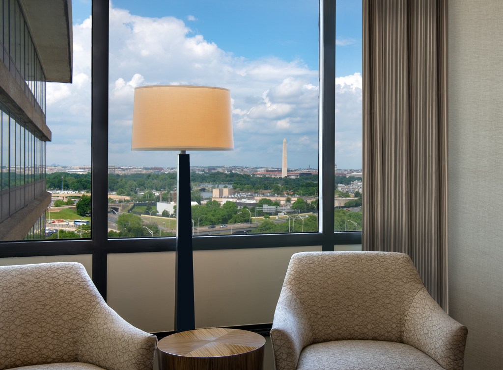 DoubleTree by Hilton Washington DC - Crystal City - Guest Room - two chairs and lamp in front of large window overlooking Washington D.C. skyline