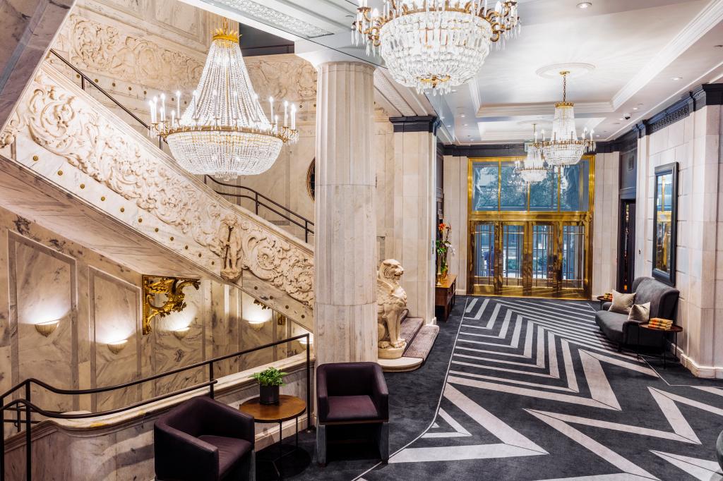 The Candler Hotel Atlanta, Curio Collection by Hilton - Lobby with chandeliers, black and white geometric carpeting, gold doors, and large ornate staircase