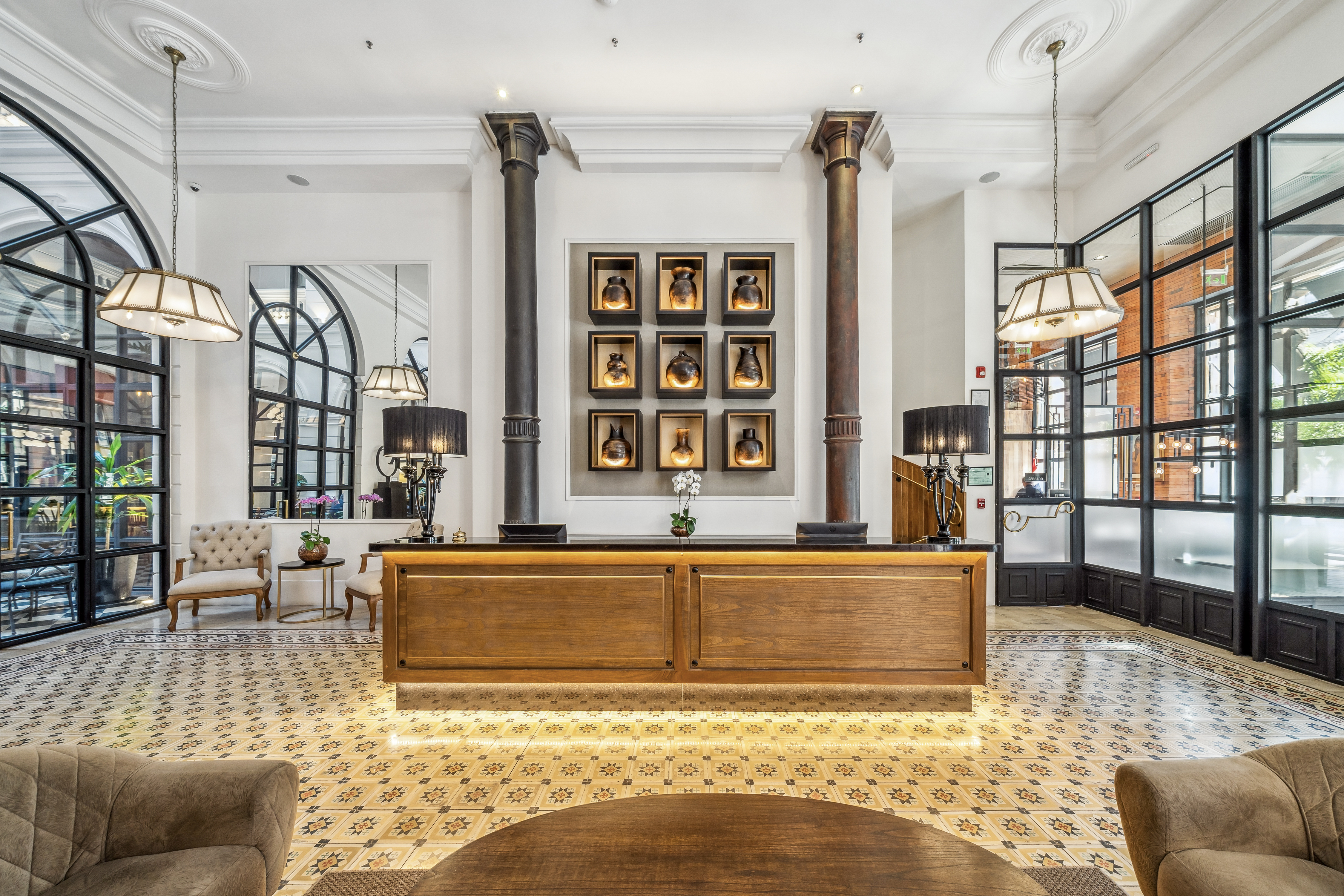 Palmaroga Hotel Asuncion, Tapestry Collection by Hilton, Front Desk, tiled flooring, seating area, black framed windows, vase display, table lamp, white pendant lights, potted plants, tan lounge chair